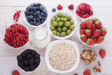 Breakfast - berries, fruit and muesli on white wooden