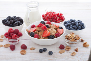 Breakfast - berries, fruit and muesli on white wooden