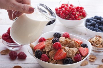 Breakfast - berries, fruit and muesli on white wooden