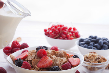 Breakfast - berries, fruit and muesli on white wooden