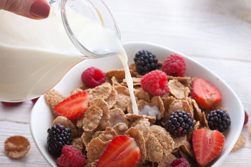 Breakfast - berries, fruit and muesli on white wooden
