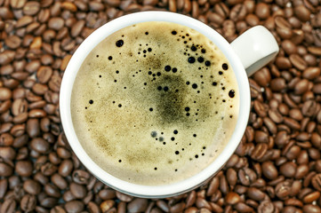 Coffee bean background with cup of fresh hot coffee close