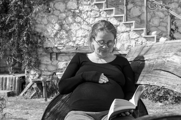 pregnant woman reading book outdoors