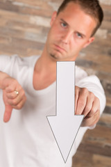 Junger Mann mit Pfeil nach unten in der Hand // Abstieg, schlecht, ungut, böse, runter