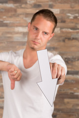 Junger Mann mit Pfeil nach unten in der Hand // Abstieg, schlecht, ungut, böse, runter