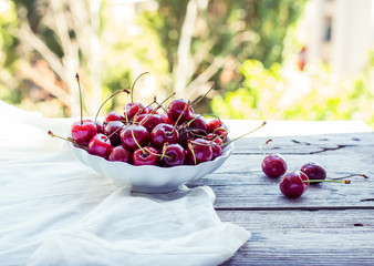 fresh red cherries in a plate, on a background of green garden,