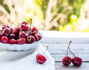 fresh red cherries in a plate, on a background of green garden,