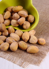 Pistachio nuts in bowl on white wooden table, healthy eating