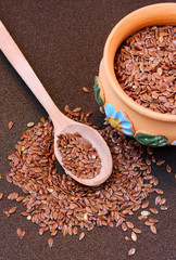 Flax seeds in a bowl with wooden spoon