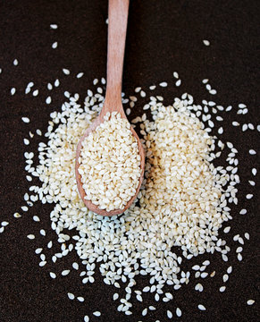 Sesame seeds in a wooden spoon on a metal background