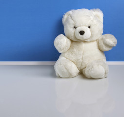 Orsacchiotto pelouche bianco con muro azzurro e base riflettente