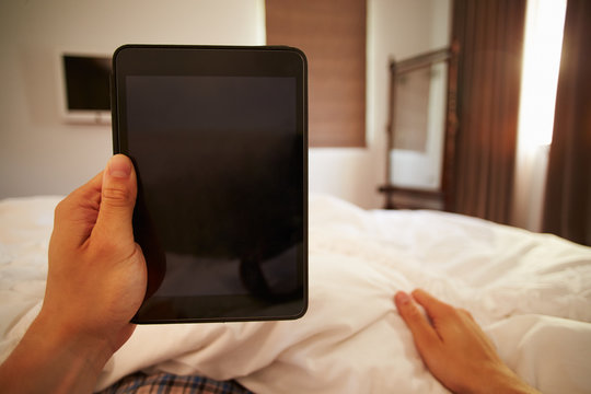Point Of View Image Of Man In Bed Looking At Digital Tablet