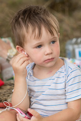 Little cute kid listening to music on headphones