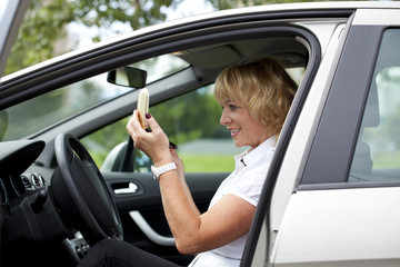 Fototapeta na wymiar Old happy elderly driver woman 55-60 years in jacket Driving a C