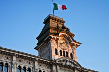 Fototapeta na wymiar Trieste, Italy -Unity of Italy Square, detail of City Hall tower with clock, quarter bell and Italian flag