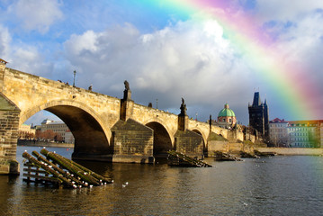 Fototapeta na wymiar Rainbow in the sky above Charles' Bridge in Prague, Czech Republic, on a sunny day, just after rain. Cityscape with dramatic sky.