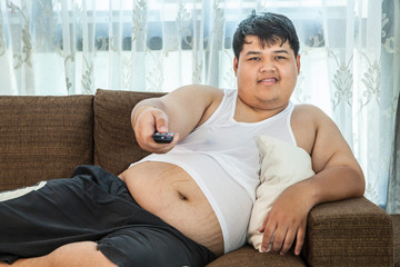 Overweight guy sitting on the couch to watch some TV