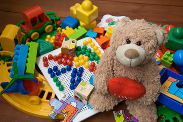 teddy bear surrounded by plastic toys