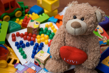 teddy bear surrounded by plastic toys