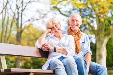 Älteres Paar sitzt auf Park Bank im Herbst - obrazy, fototapety, plakaty