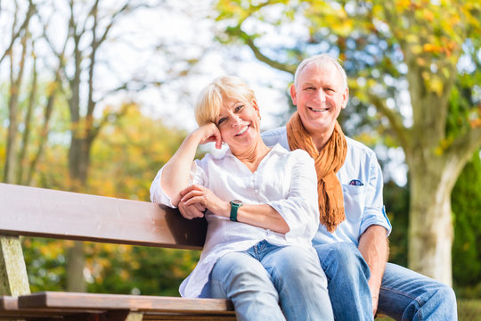 Älteres Paar sitzt auf Park Bank im Herbst