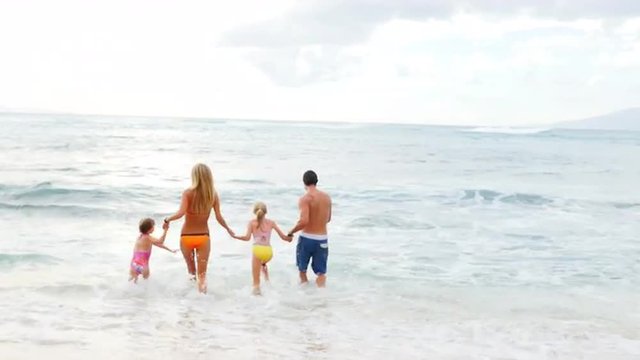 Family running in and out of the ocean