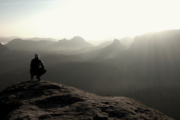 Hiker sits on a rocky peak and enjoy the mountains scenery