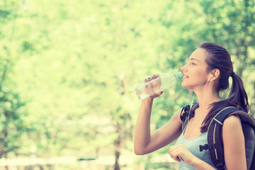 happy young woman hiker with backpack drinking bottled water