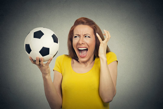 Angry frustrated woman screaming at soccer ball