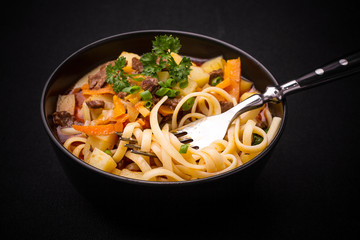 Uzbek noodle soup Lagman on black