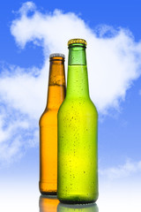 Two Cold frosted beer in green and golden brown bottle frosted 