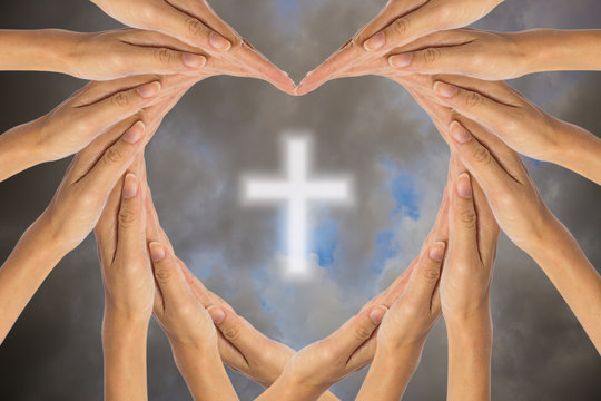 Hands make heart shape and Christian cross in the sky.