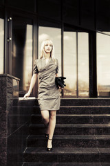 Young fashion business woman with handbag on the steps against o