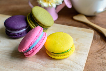 Colorful macaroons and a cup of coffee on wooden table