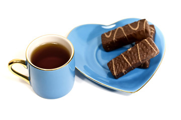 Cup with tea and a saucer with sweets on a white background