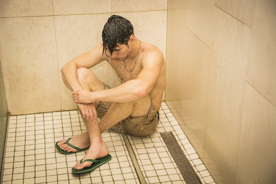 Sad Young Man Taking Shower, Sitting On Floor