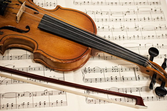 Old violin and bow on musical notes