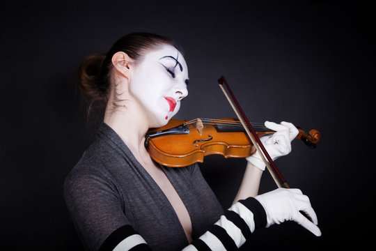 Woman mime in white gloves who plays the violin