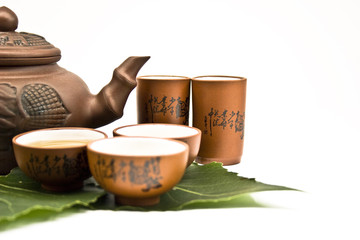 Clay teapot and cups with tea leaves