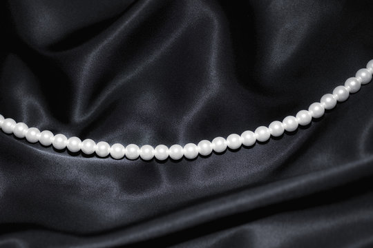 white pearl necklace on black silk