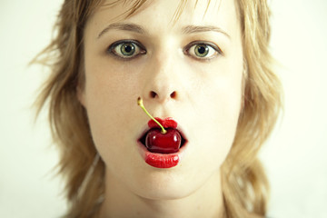 young beautiful girl with cherry in mouth