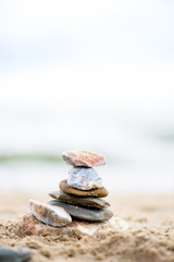 Stones pyramid on sand. Sea in the background