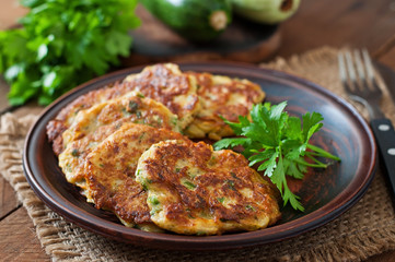 Zucchini pancakes with parsley on a wooden table.