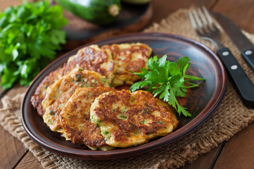 Zucchini pancakes with parsley on a wooden table.