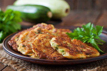 Zucchini pancakes with parsley on a wooden table.