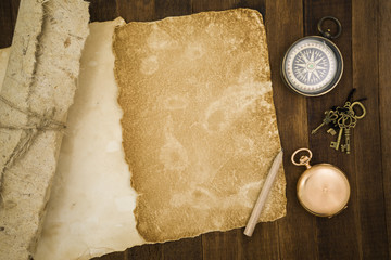 Old paper, compass, pocket watch on wooden background