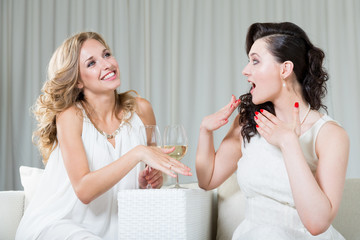 Best friends sitting in the cafe, drinking wine and talking about engagement.