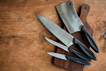 Set of kitchen knifes on wooden cutting board on old wooden tabl - obrazy, fototapety, plakaty
