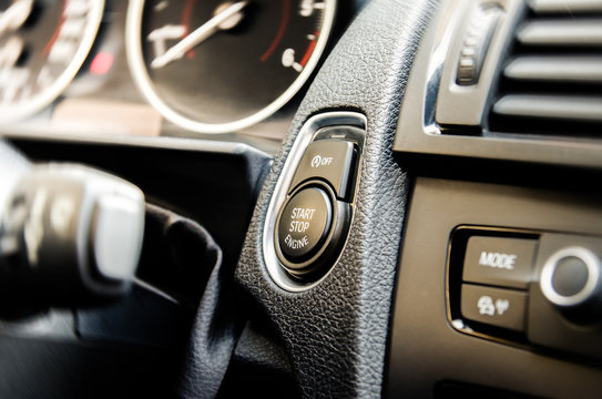 Auto Start And Stop Button On A Modern Premium Car Interior Suggesting Fuel Economy, Modern Technology And Eco Friendlyness On A Bright Sunny Day With Some Light Filters Applied