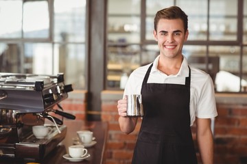 Smiling barista holding jug with milk 